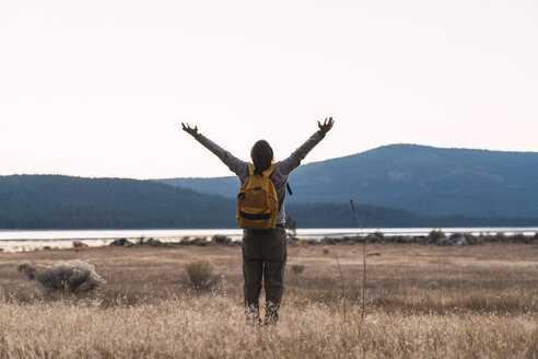 USA, Nordkalifornien, Rückansicht eines jungen Mannes mit erhobenen Armen auf einem Wanderausflug in der Nähe des Lassen Volcanic National Park - KKAF03002