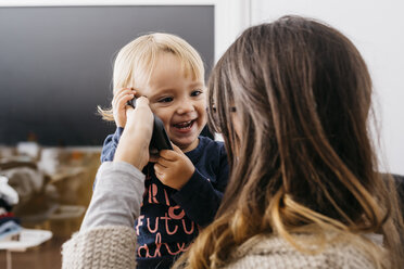 Mutter gibt Handy an glückliche kleine Tochter zu Hause - JRFF02110