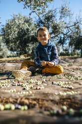 Porträt eines lächelnden Jungen, der mit Oliven in einem Olivenhain spielt - JRFF02126