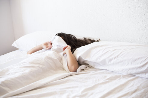 Mädchen liegt im Bett und bedeckt ihr Gesicht mit einer Decke - ERRF00067