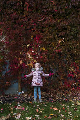 Girl throwing autumn leaves in the air in the garden - PSIF00168