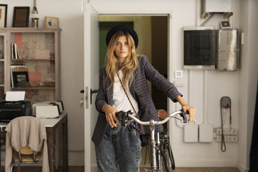 Porträt einer jungen Frau mit Fahrrad in einem Atelier - ERRF00085