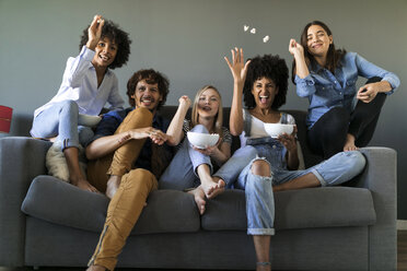 Exuberant friends sitting on couch watching tv - VABF01734