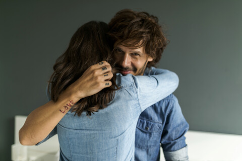Lächelnder tätowierter Mann umarmt Freundin, lizenzfreies Stockfoto