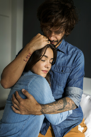 Tätowierter Mann umarmt Freundin, lizenzfreies Stockfoto