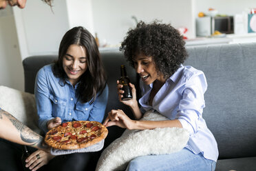 Tätowierter Mann bietet Freunden auf der Couch sitzend Pizza an - VABF01811