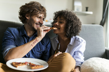 Glückliches Paar sitzt auf der Couch und isst Pizza - VABF01817