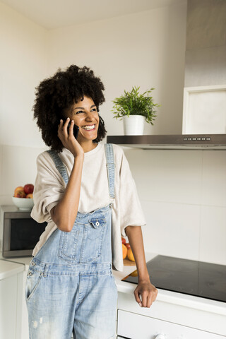 Glückliche Frau am Handy in der Küche zu Hause, lizenzfreies Stockfoto
