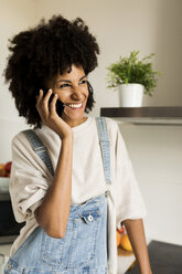 Happy woman on cell phone in kitchen at home - VABF01837