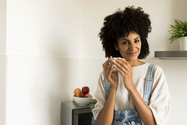 Portrait of smiling woman holding cup in kitchen at home - VABF01840