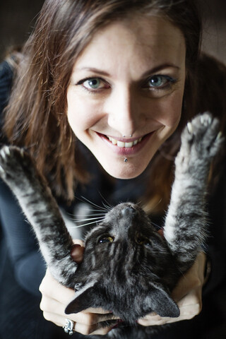 Porträt einer lächelnden Frau und ihrer grau getigerten Katze, lizenzfreies Stockfoto