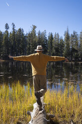 USA, Kalifornien, Yosemite-Nationalpark, Wanderer steht auf einem Baumstamm im Herbst - KKAF03012