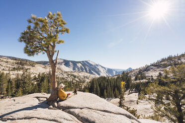 USA, Kalifornien, Yosemite National Park, Wanderer lehnt sich an einen Baum - KKAF03015