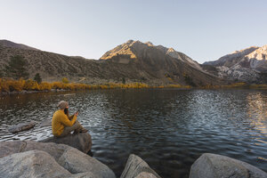 USA, Kalifornien, Yosemite-Nationalpark, Mammoth-Seen, Wanderer mit Smartphone am Convict Lake - KKAF03028