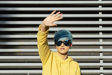 Portrait of young woman with dyed blue hair wearing mirrored sunglasses and yellow hooded jacket - ERRF00111