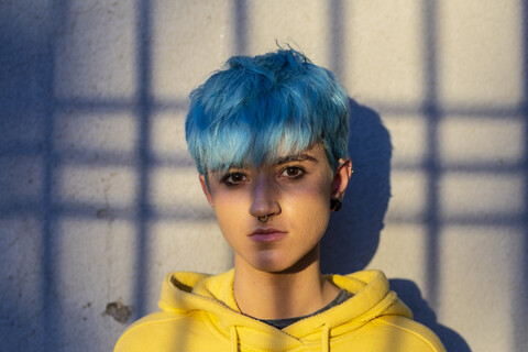 Porträt einer jungen Frau mit blau gefärbtem Haar und Nasenpiercing, lizenzfreies Stockfoto