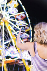 Rückansicht eines Teenagers, der ein Riesenrad auf der Messe fotografiert - FBAF00176