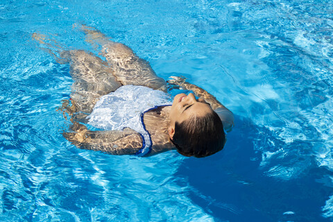 Junge Frau schwimmt auf dem Wasser im Schwimmbad, lizenzfreies Stockfoto