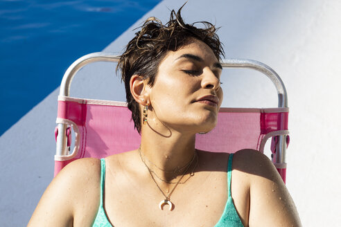 Porträt einer jungen Frau, die sich auf einer Sonnenliege am Schwimmbad entspannt - ERRF00139