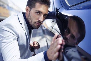 Young businessman stroking his polished car - JSRF00082