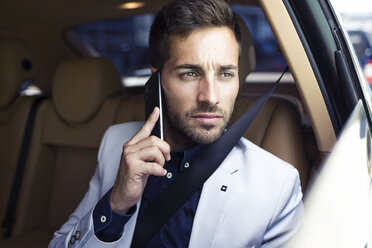 Junger Geschäftsmann sitzt im Auto und benutzt sein Smartphone - JSRF00085