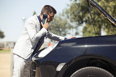 Young businessman having a car breakdown, talking on the phone - JSRF00101