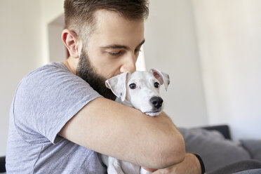 Man cuddling his dog at home - ZEDF01774