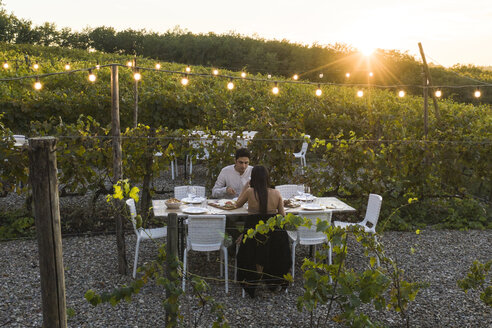 Italien, Toskana, Siena, junges Paar beim Abendessen in einem Weinberg - FBAF00181