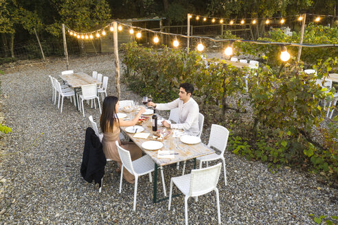 Italien, Toskana, Siena, junges Paar beim Abendessen in einem Weinberg - FBAF00184