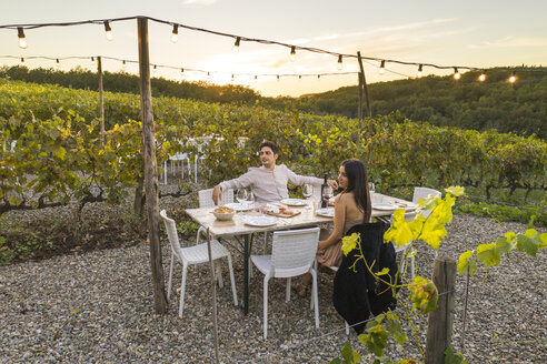 Italien, Toskana, Siena, junges Paar beim Abendessen in einem Weinberg - FBAF00189