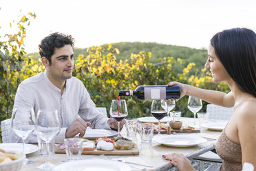 Italien, Toskana, Siena, junges Paar beim Abendessen in einem Weinberg mit Rotwein - FBAF00205