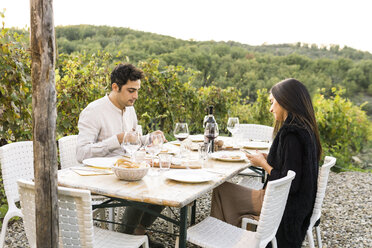 Italien, Toskana, Siena, junges Paar beim Abendessen in einem Weinberg - FBAF00212