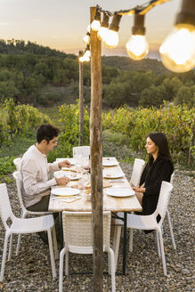 Italien, Toskana, Siena, junges Paar beim Abendessen in einem Weinberg - FBAF00213