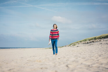 Ältere Frau geht barfuß am Strand - MOEF01569