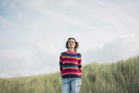 Content woman standing in the dunes, smiling - MOEF01581