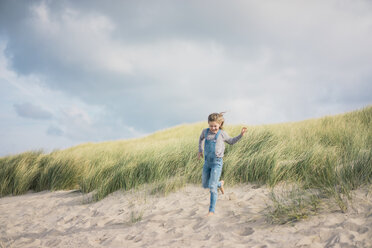 Glückliches Mädchen, das am Strand Spaß hat und in den Dünen läuft - MOEF01596
