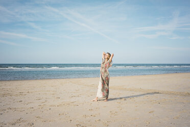 Mature woman stretching on the beach, enjoying the sun - MOEF01606