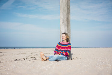 Reife Frau entspannt sich am Strand und stützt sich auf eine Stange - MOEF01613