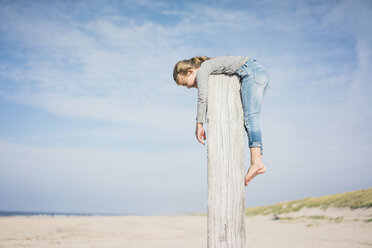 Kleines Mädchen am Strand, das an einer Stange hängt - MOEF01620