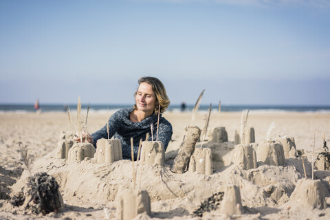 Ältere Frau baut eine Sandburg am Strand, lizenzfreies Stockfoto