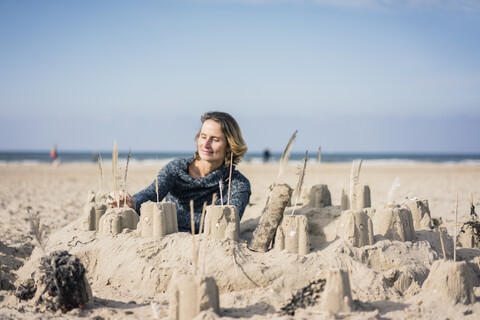 Mature woman building a sandcastle on the beach stock photo