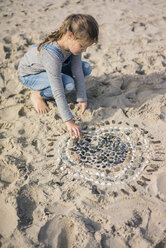 Kleines Mädchen macht ein Herz aus Muscheln am Strand - MOEF01624