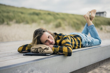 Reife Frau mit Laptop, auf der Promenade am Strand liegend, entspannend - MOEF01646