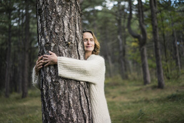 Woman hugging tree in forest - MOEF01648