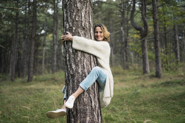 Woman hugging tree in forest - MOEF01649