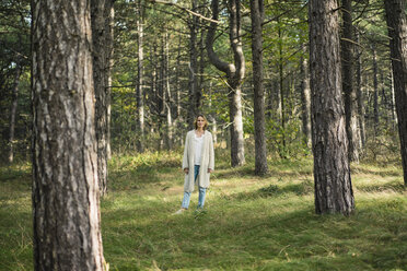 Serene woman standing in the forest - MOEF01650