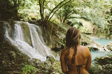 Junge Frau im Bikinioberteil mit Blick auf einen Wald - CAVF56049