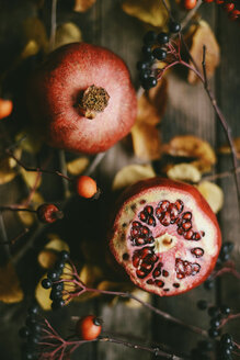 Blick von oben auf Granatäpfel mit Beeren und Blättern auf einem Holztisch - CAVF56069