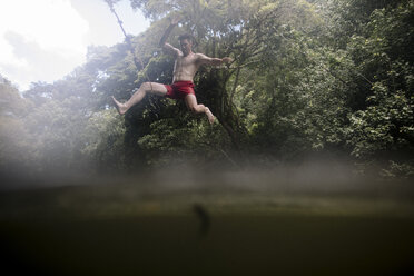 Niedriger Winkel Blick auf hemdsärmelig energischen Mann taucht in See im Wald - CAVF56083