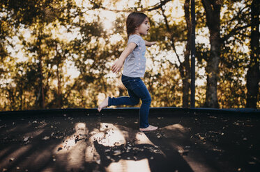 Side view of girl running on footpath by trees - CAVF56123